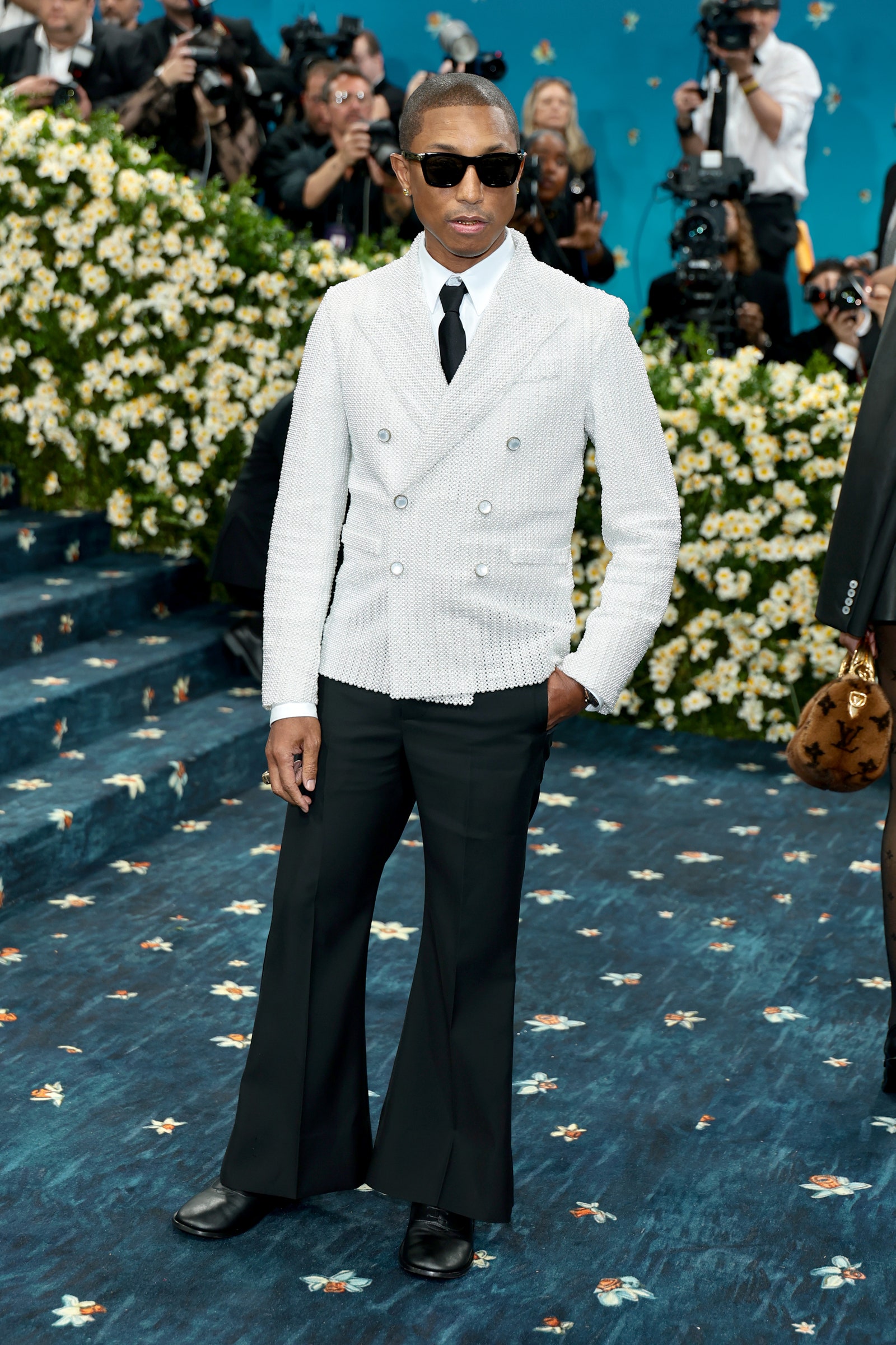 Images may contain Pharrell Williams clothing formally wearing suit staff standing accessories handbags and adults